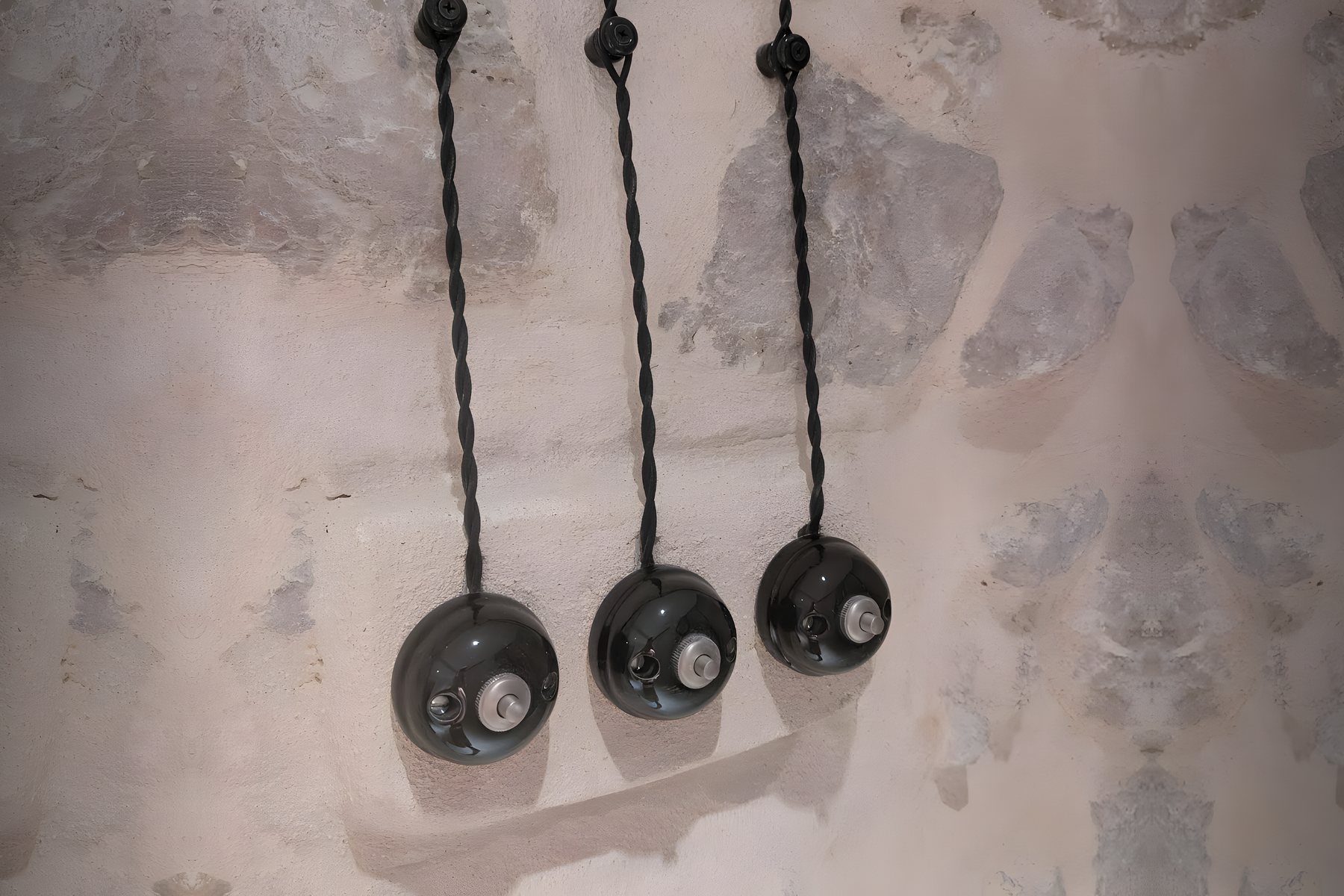 Interrupteurs en porcelaine posés proprement en saillie sur un mur en pierre par ELM Électricité