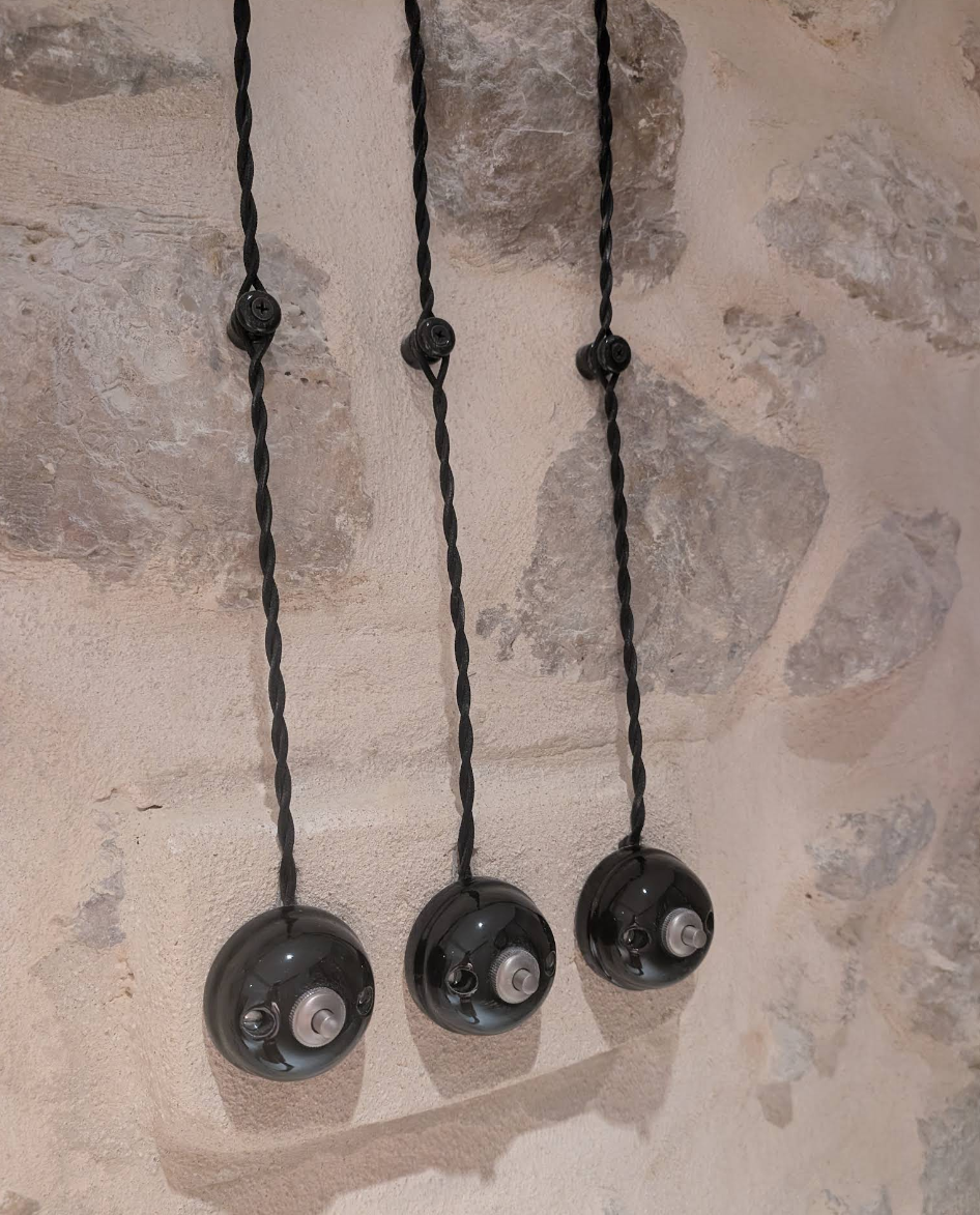 Interrupteurs en porcelaine sur câble torsadé posés en saillie sur un mur en pierre